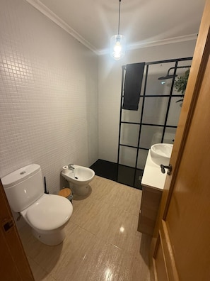 Een kleine badkamer met toilet, bidet en wastafel.