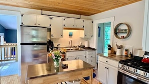A modern kitchen with stainless steel appliances, white cabinetry, and a wooden island.