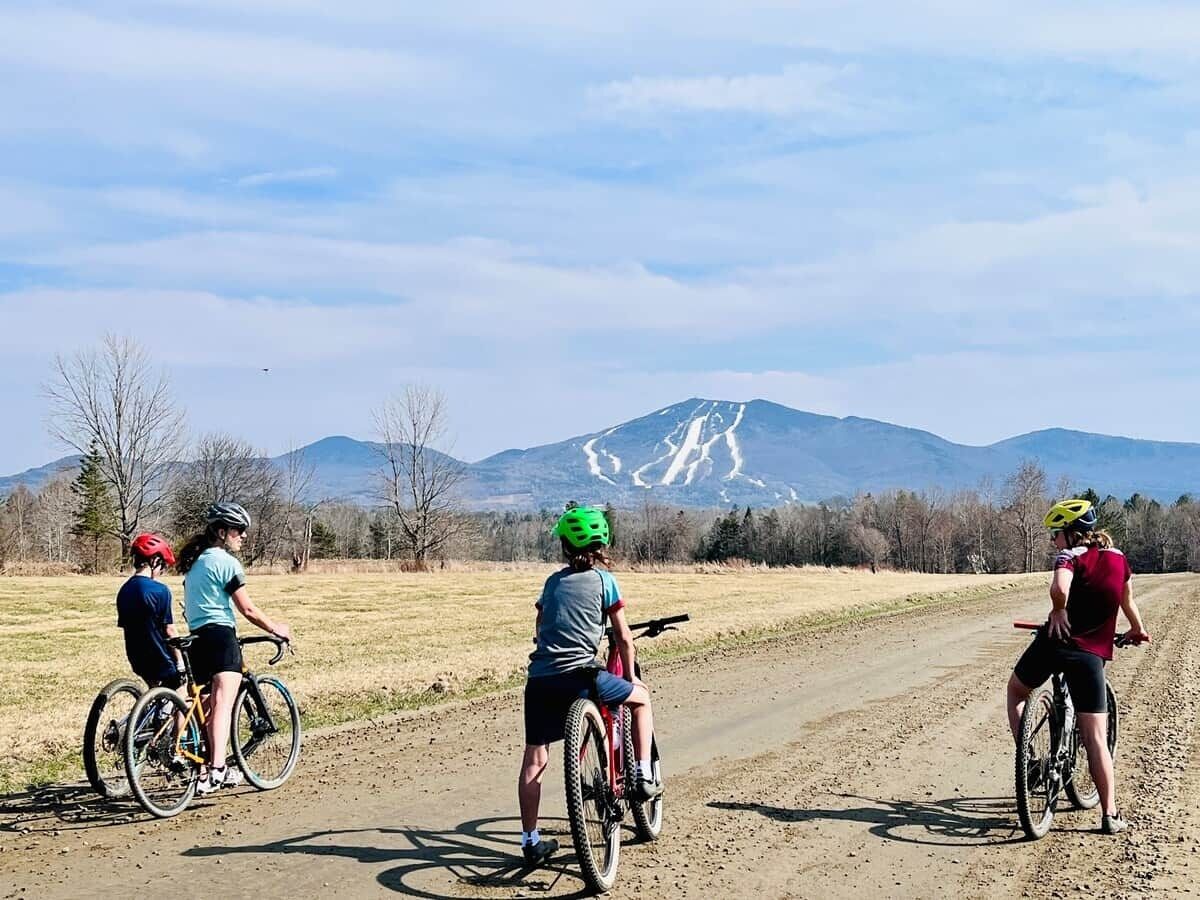 Quatre cyclistes sur un chemin de terre, avec une montagne en arrière-plan.