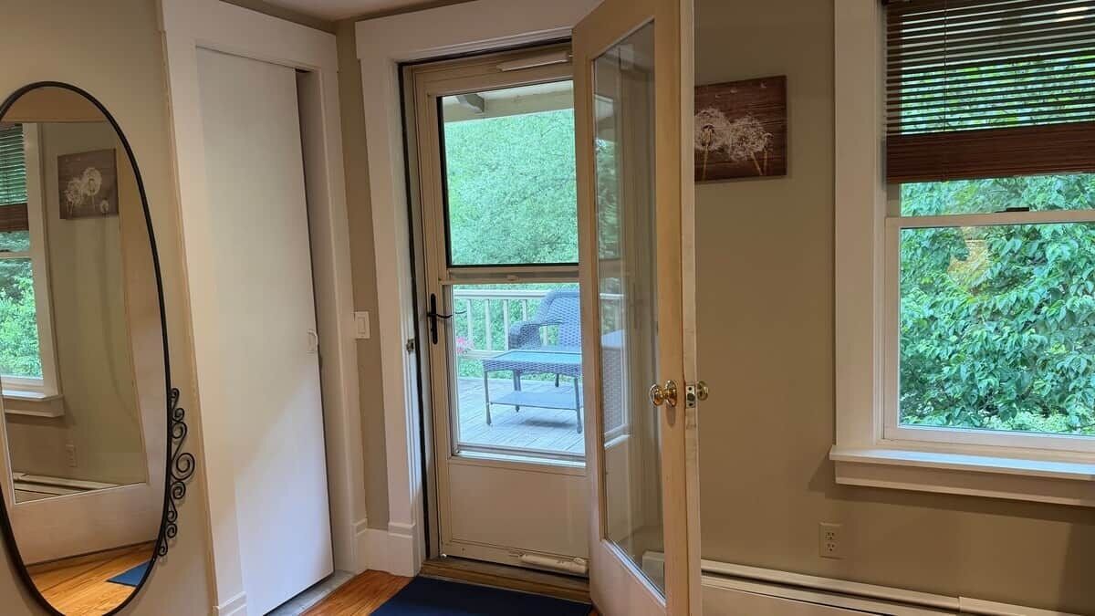 A door leading to an outdoor deck with a view of greenery.