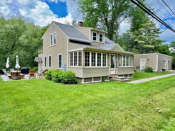 A two-story house with a large front porch, a covered patio area, and a well-maintained lawn.