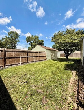 Ein Garten mit Holzzaun, Baum und Haus.