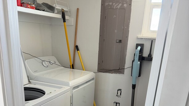 A laundry room with a front-loading washer and dryer, a broom, a mop, and a window with a view. - Your perfect beach getaway is waiting! 3 bedroom 2 1/2 bathroom beach house. (St. Augustine)