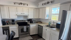 A modern kitchen with white cabinets, stainless steel appliances, and a wooden floor. - Your perfect beach getaway is waiting! 3 bedroom 2 1/2 bathroom beach house. (St. Augustine)