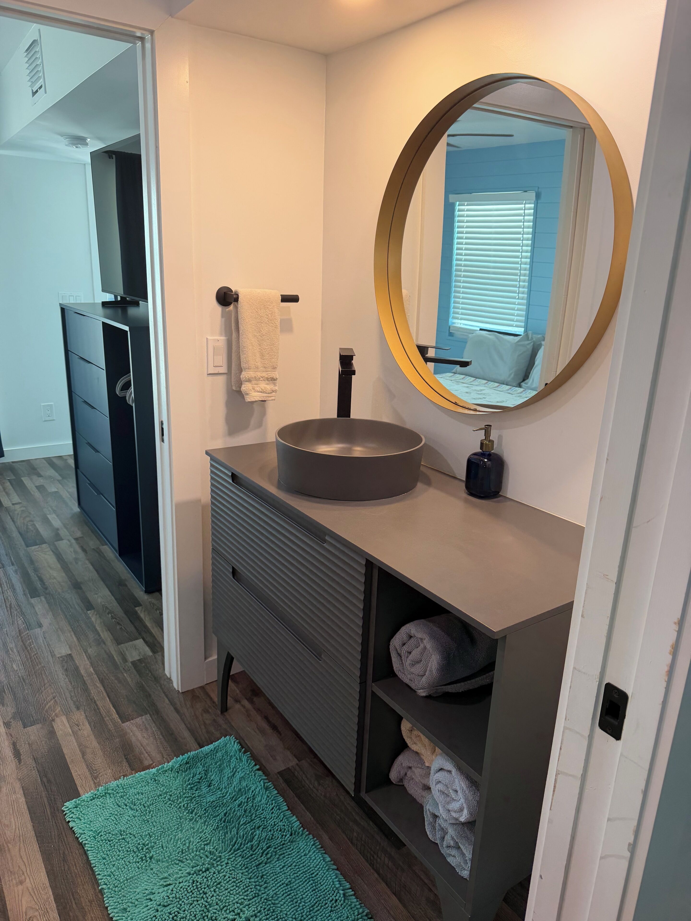 A modern bathroom with a round mirror, a sink, and a towel rack.
