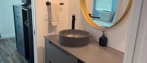 A modern bathroom with a round mirror, a sink, and a towel rack.