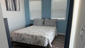 A bedroom with a bed, two bedside tables, and a window with blinds. - Your perfect beach getaway is waiting! 3 bedroom 2 1/2 bathroom beach house. (St. Augustine)