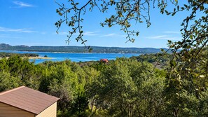 Blick auf die Küste mit einem Haus und üppigem Grün im Vordergrund, einem klaren Himmel und einer entfernten Küstenlinie.