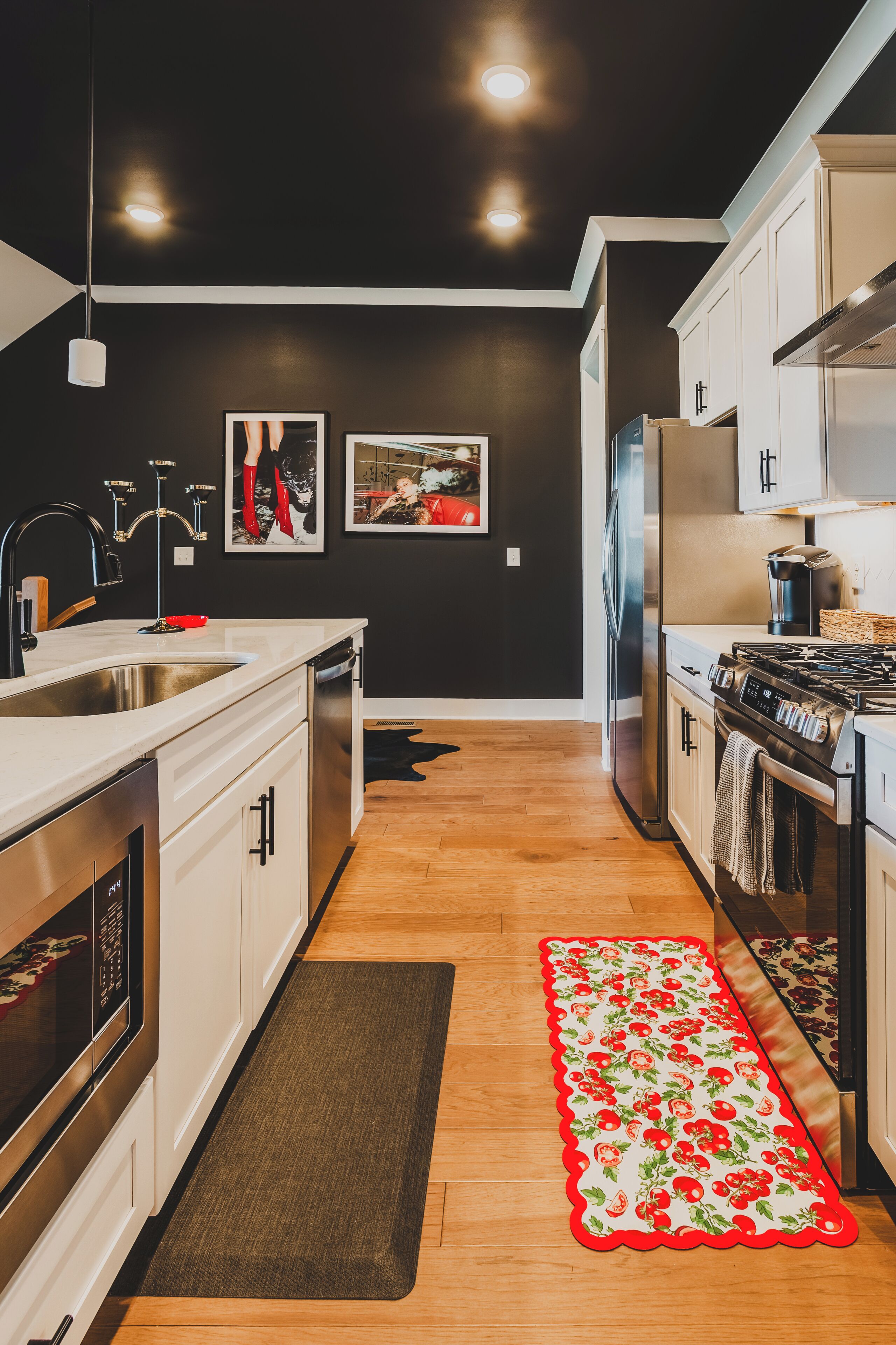 Una cocina moderna con electrodomésticos de acero inoxidable, piso de madera y un tapete con estampado rojo y blanco.