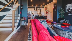 Et moderne interiør med trappe, opholdsstue med rød sofa og et køkken i baggrunden.