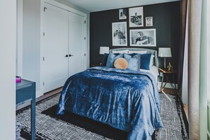 A bedroom with a bed, bedside tables, a wardrobe, and wall art. - Nashville Legendz: Rooftop Deck (Nashville)