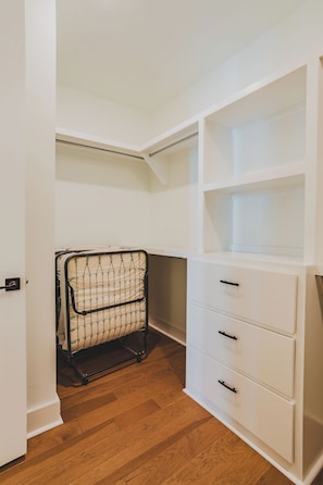 Ein Zimmer mit einem weißen Stauraum, einem Metallgestell mit Netz und Holzboden.