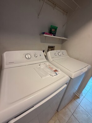 A laundry area with two front-loading washers and dryers, a shelf with a bag of detergent, and a power outlet. - Lake Access 3 Bedroom Townhome Near Chic's Beach & Airport (Virginia Beach)