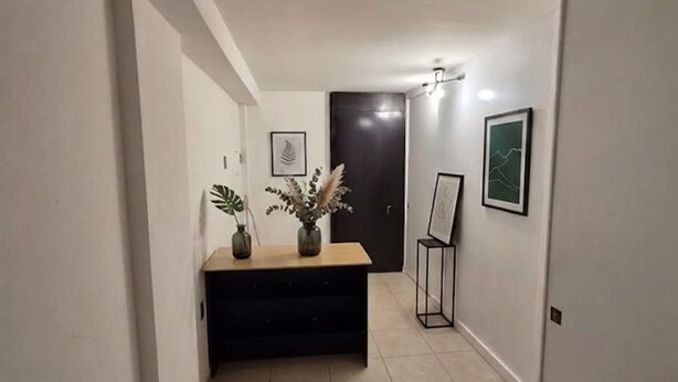 A hallway with a bench, framed artwork, and a door. - Capsule (Mexico City)