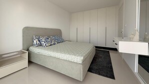 A bedroom with a bed, a bedside table, a wardrobe, and a mirror.