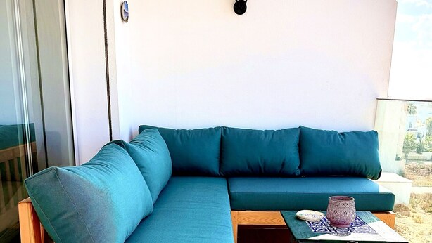 A modern outdoor seating area with a wooden-framed sofa and a small table.