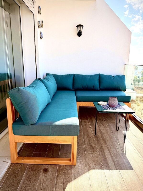 A modern outdoor seating area with a wooden-framed sofa and a small table.