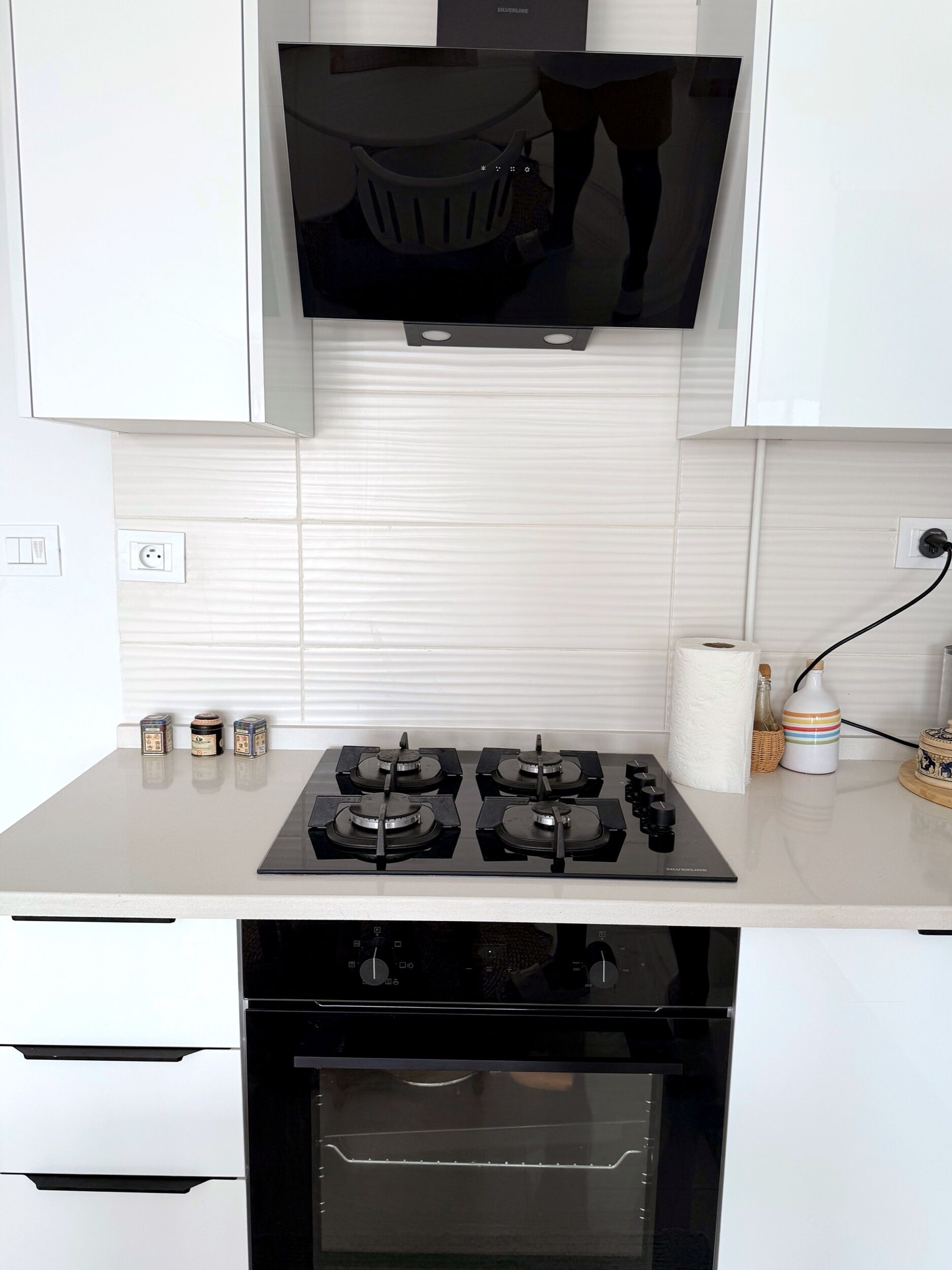 A kitchen with a gas stove, oven, and a flat-screen TV mounted above the counter.