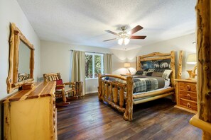 A bedroom with a wooden bed, a ceiling fan, a window with curtains, and a wooden dresser. - Hilltop Lodge -  27 Guests, 5 bedroom + loft beds (Broken Bow)