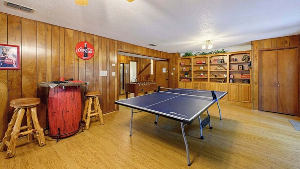 Una mesa de ping pong en una habitación con paredes de madera y un letrero de Coca-Cola.