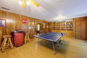 A ping pong table in a room with wooden walls and a Coca-Cola sign.