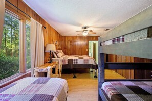 A bedroom with two beds, a desk, a chair, and a ceiling fan.