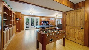 Una habitación con paneles de madera, una mesa de fútbol de mesa y una mesa de billar.