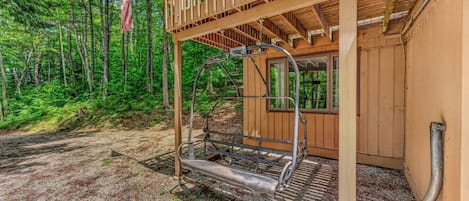 Una cabaña de madera con una escalera metálica que sube a un balcón.