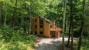 Eine Holzhütte mit Kiesweg, umgeben von dichtem Wald.