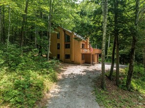A wooden cabin with a gravel path leading to it, surrounded by dense forest. - The Summit House at Waterville Estates w/Amenities (Campton)
