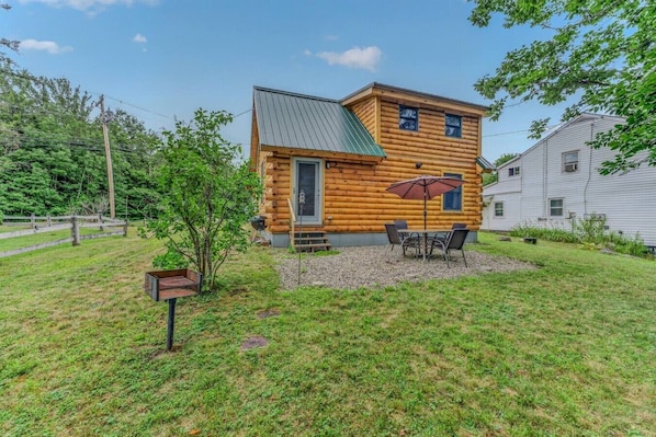 A log cabin with a patio, a small table with chairs, and a covered umbrella.
