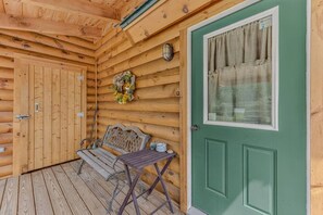 A wooden cabin with a green door, a bench, and a table outside.