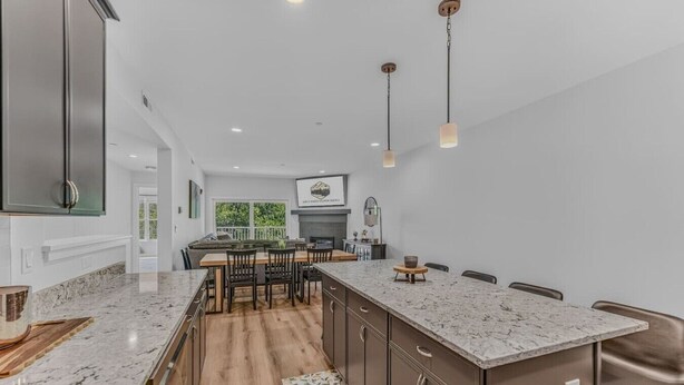 A modern kitchen with a central island, wooden flooring, and pendant lighting. - Luxe Condo at Forest Ridge- Amenities & Central AC (Lincoln)