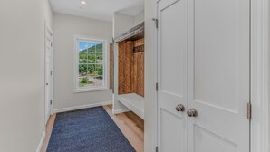 A hallway with a view of a green landscape through a window, a wooden wall, and a white door. - Luxe Condo at Forest Ridge- Amenities & Central AC (Lincoln)