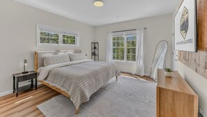 A bedroom with a bed, bedside tables, a nightstand, a window with curtains, a framed picture on the wall, and a wooden floor. - Luxe Condo at Forest Ridge- Amenities & Central AC (Lincoln)
