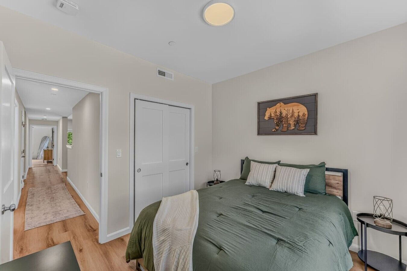 Ein Schlafzimmer mit einem Bett, einer Tür, einem Flur und einem an der Wand hängenden Bild.