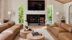 Ein Wohnzimmer mit Ledersofas, Kamin, Fernseher und einem großen Fenster.