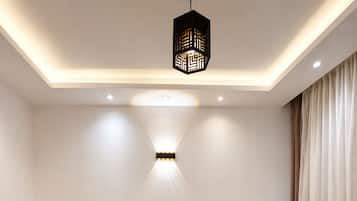 Une chambre avec deux lits simples, une table de chevet, une lampe fixée au mur et un luminaire au plafond.