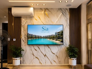 Un hall d’hôtel doté d’un grand écran de télévision diffusant des images de «
Sia Lagoon
» et d’un mur de marbre parcouru de veines dorées.