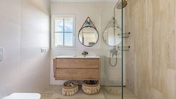 A modern bathroom with a wooden vanity, a glass shower enclosure, and a large mirror.
