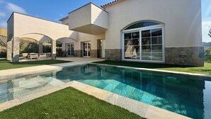A modern house with a swimming pool, stone accents, and a patio area.