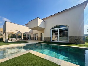 A modern house with a swimming pool, stone accents, and a patio area.