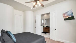 A bedroom with a bed, a ceiling fan, and a view into the kitchen. - Afrotique HOU Getaway Pool!Galleria!Uptown (Houston)