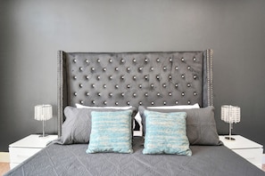 A bed with a tufted headboard, two pillows, and two bedside tables with lamps. - Afrotique HOU Getaway Pool!Galleria!Uptown (Houston)