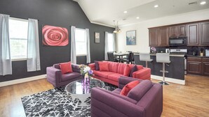 A modern living room with a sectional sofa, a coffee table, and a dining area with a table and chairs. - Afrotique HOU Getaway Pool!Galleria!Uptown (Houston)