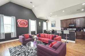 A modern living room with a sectional sofa, a coffee table, and a dining area with a table and chairs. - Afrotique HOU Getaway Pool!Galleria!Uptown (Houston)
