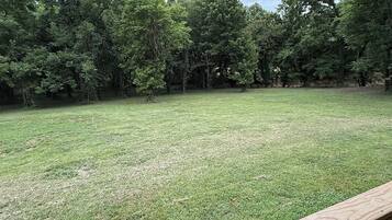A wooden deck with a view of a grassy yard and trees.