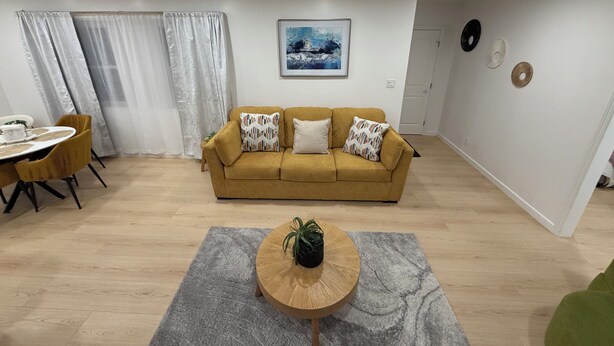 A living room with a sofa, a dining table, and a coffee table. - Your Ideal Stay Near Disney (Placentia)