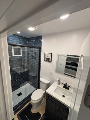 Une petite salle de bain comprenant une douche, des toilettes et un lavabo.