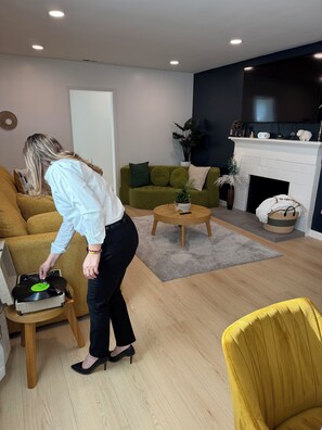 A living room with a sofa, a coffee table, a fireplace, and a television. - Your Ideal Stay Near Disney (Placentia)